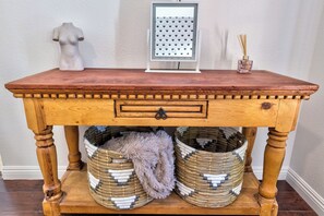 A wooden table with a drawer, two woven baskets, a decorative item, and a small mirror. - Tropical Boho 3 bdrm house w/pool and pets are welcome. (Las Vegas)