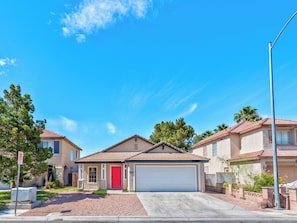 A residential house with a red door, a garage, and a driveway. - Tropical Boho 3 bdrm house w/pool and pets are welcome. (Las Vegas)
