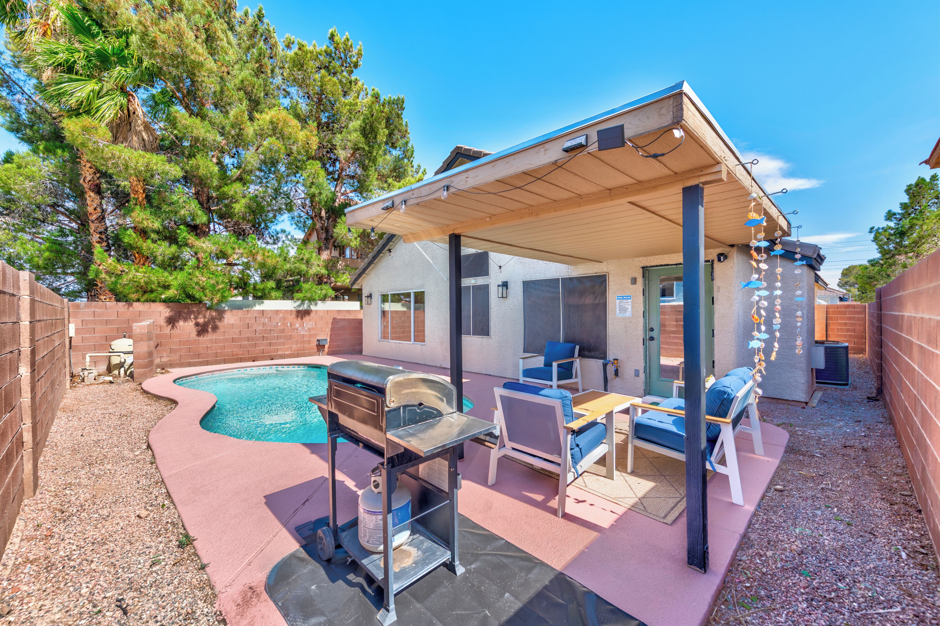 A backyard with a pool, a barbecue grill, and outdoor seating.