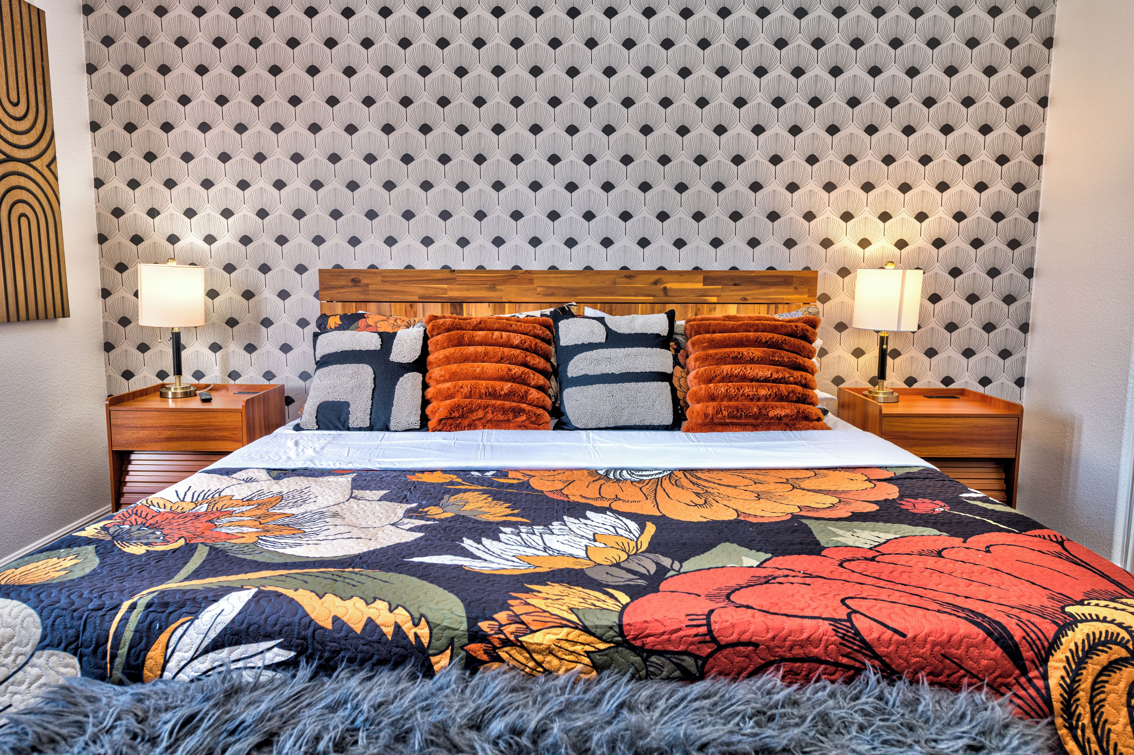 A bed with a floral comforter, wooden headboard, and multiple pillows.