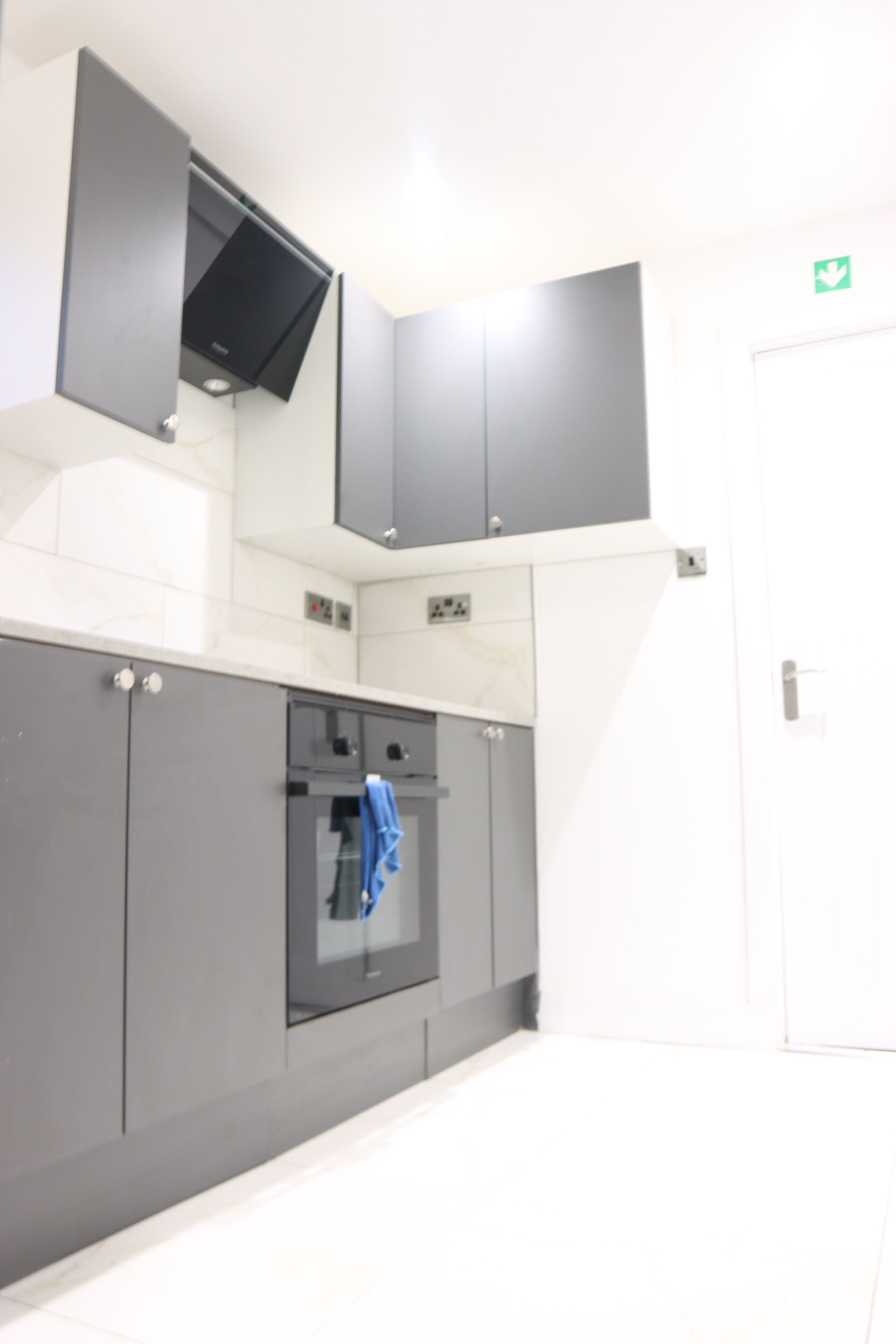 A modern kitchen with grey cabinets, a built-in oven, and a microwave.