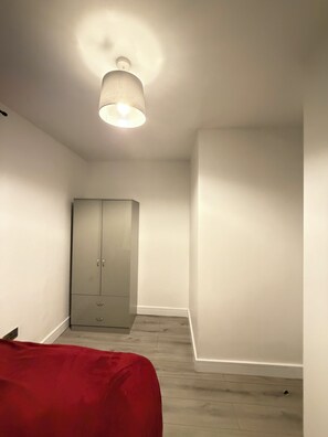 Una habitación con armario, cama y lámpara en el techo.