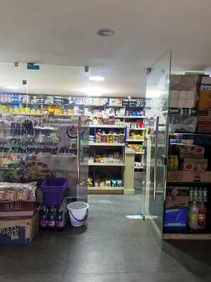 A store with glass doors, shelves stocked with various products, and a visible sign indicating 'Our Neighborhood.' - Elegant Studio in kiambur road,fast Wifi & Free Parking (Nairobi)