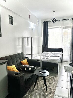 A modern hotel room with a sofa, a bed, a small table, and a TV. - Elegant Studio in kiambur road,fast Wifi & Free Parking (Nairobi)