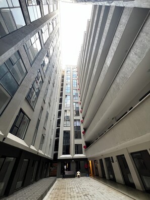 En bygning med flere etager, en central gårdsplads, store vinduer og et moderne arkitektonisk design.