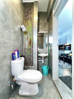 Et moderne badeværelse med toilet, håndvask og bruseområde.