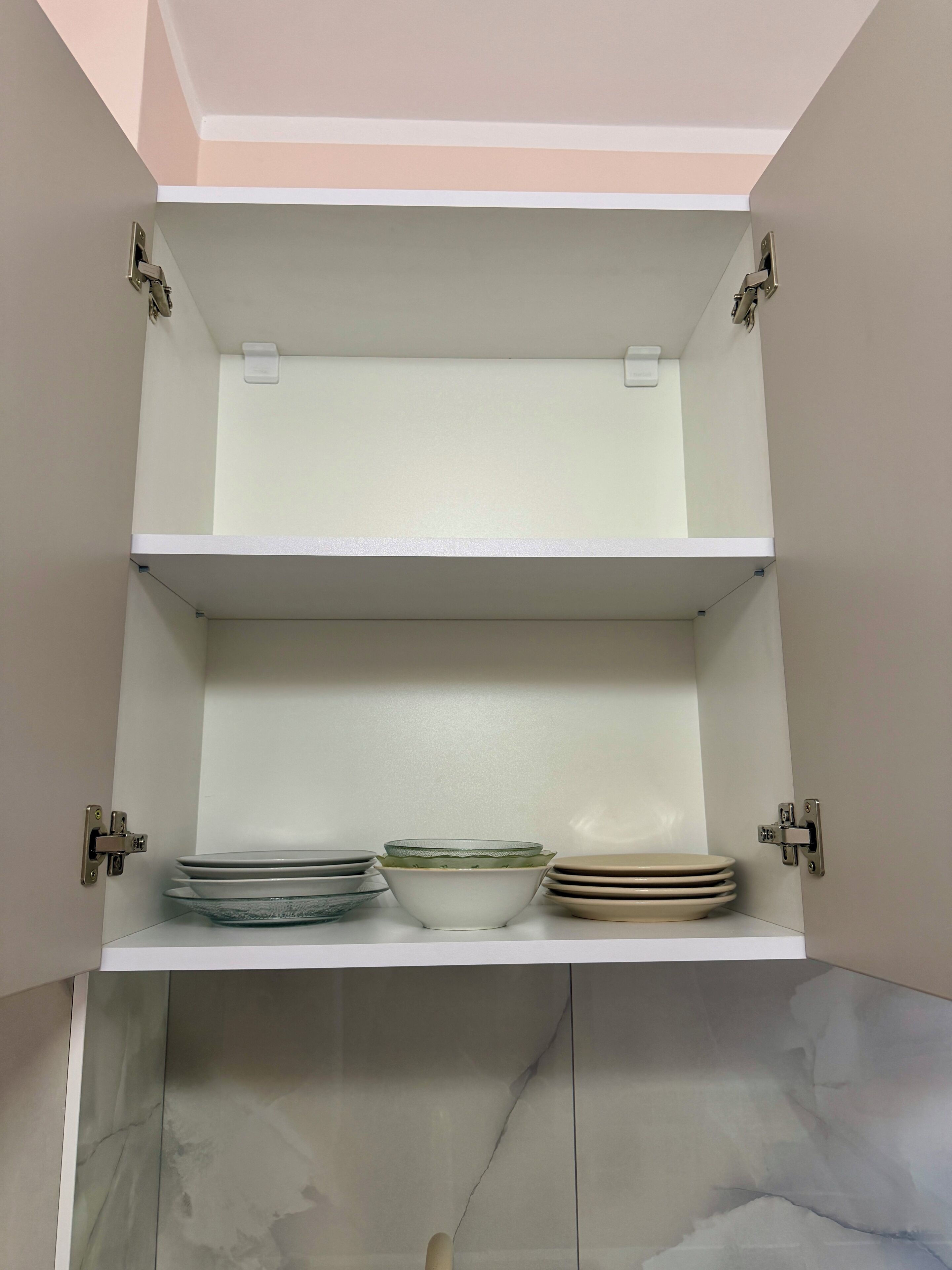 Un meuble de cuisine à deux étagères, dont l’une contient des assiettes et des bols.