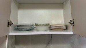 Un mueble de cocina con dos estantes, uno de ellos con platos y cuencos.