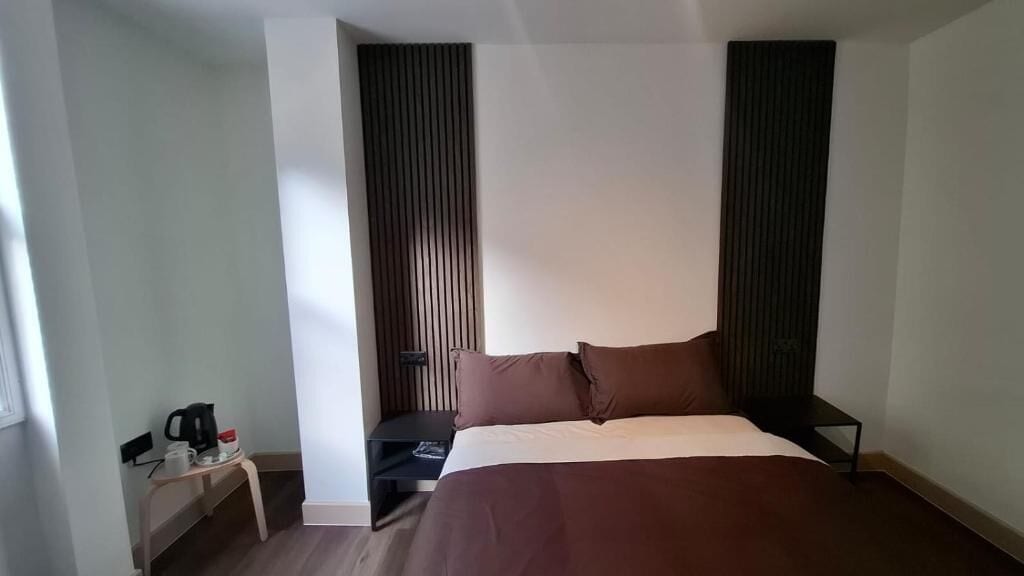 A hotel room with a bed, bedside tables, a nightstand, a coffee maker, and a window.