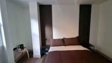 A hotel room with a bed, bedside tables, a nightstand, a coffee maker, and a window.