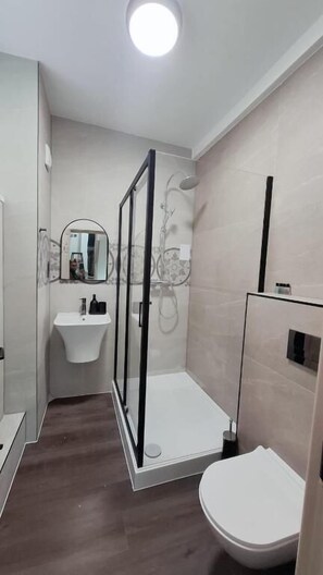A modern bathroom with a shower, toilet, and sink.