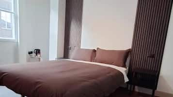 A modern bedroom with a large bed, a bedside table, and a window.