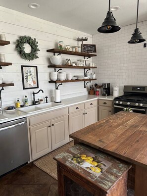 A kitchen with white cabinetry, a wooden island, and pendant lighting. - Tejas Hills Johnson City (Johnson City)