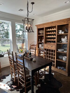 A dining area with a wooden table and chairs, a wine rack, and a cowhide rug. - Tejas Hills Johnson City (Johnson City)