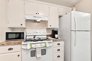 A kitchen with a white stove, microwave, and refrigerator. - Tejas Hills #1 & #2 | Hill Country Pool Retreat (Fredericksburg)