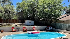 Ein Garten mit Pool, roten Stühlen und einer sternförmigen Struktur.