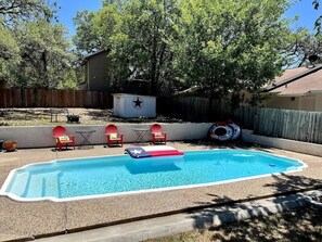 A backyard with a swimming pool, red chairs, and a star-shaped structure. - Tejas Hills #1 & #2 | Hill Country Pool Retreat (Fredericksburg)