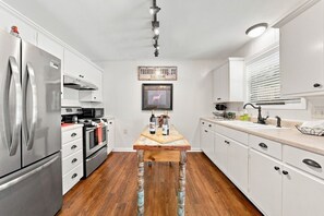 Eine moderne Küche mit Edelstahlgeräten, einem Holztisch und weißen Schränken.