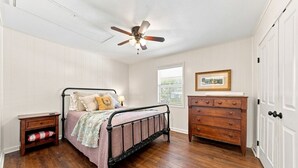 Un dormitorio con cama, mesita de noche, cómoda y ventilador de techo.