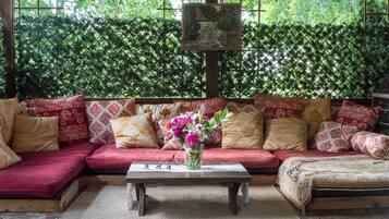 Uma área de estar aconchegante com um sofá e uma mesa de centro, adornada com almofadas estampadas e um vaso de flores.