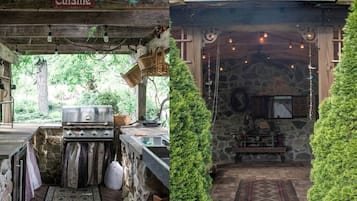 A rustic outdoor kitchen area with a grill, hanging lights, and a stone wall.
