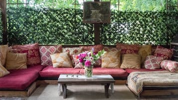 A cozy seating area with a sofa and a coffee table, surrounded by patterned cushions and a vase of flowers.