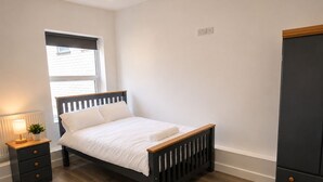 Ein Schlafzimmer mit einem Bett, einem Nachttisch, einer Lampe und einem Kleiderschrank.