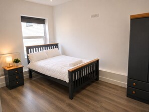 Ein Schlafzimmer mit einem Bett, einem Nachttisch, einer Lampe und einem Kleiderschrank.