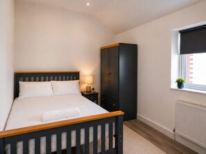 Una camera da letto con un letto, un comodino, un armadio, una finestra con vista e un termosifone.