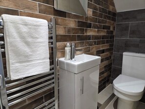 A bathroom with a white sink, a toilet, and a towel rack. - Modern 5BR Home | Sleeps 12 | Free Parking (Southampton)