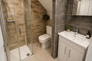 A bathroom with a glass shower enclosure, a toilet, and a sink with a mirror above. - Modern 5BR Home | Sleeps 12 | Free Parking (Southampton)