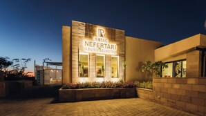 A hotel entrance with a sign for 'Rabat Neferarti Abusimbel Hotel' and a paved walkway leading to the entrance. - Retac Abu Simbel Nefertari Hotel (Abu Simbel)