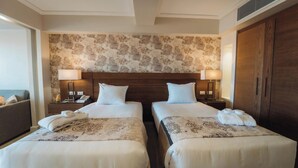 A hotel room with two beds, a wooden headboard, a patterned wallpaper, and a wardrobe. - Retac Abu Simbel Nefertari Hotel (Abu Simbel)