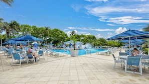 Ein Poolbereich mit Liegestühlen, Sonnenschirmen und einem Schwimmbecken.