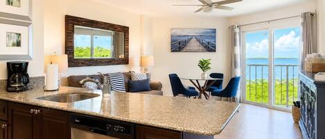 A modern kitchen with a central island, a dining area with a view, and a balcony with a view.