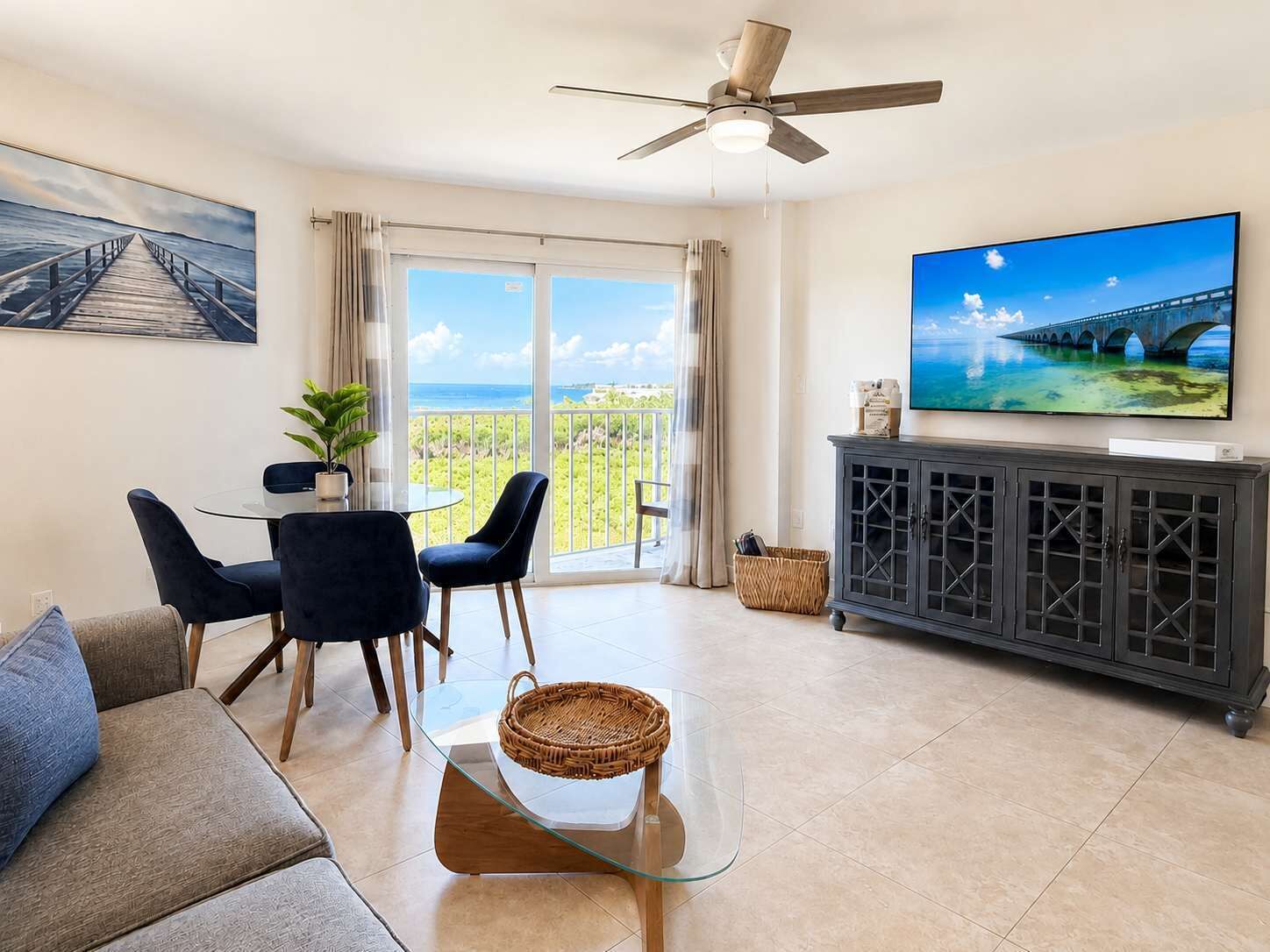A living room with a balcony, a ceiling fan, a TV, and a dining area.