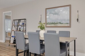 A dining area with a table and chairs, a bookshelf, a vase with flowers, and a framed picture on the wall. - Clearwater Pool Oasis -3 BR- 2 King Beds - Near Beach (Clearwater)