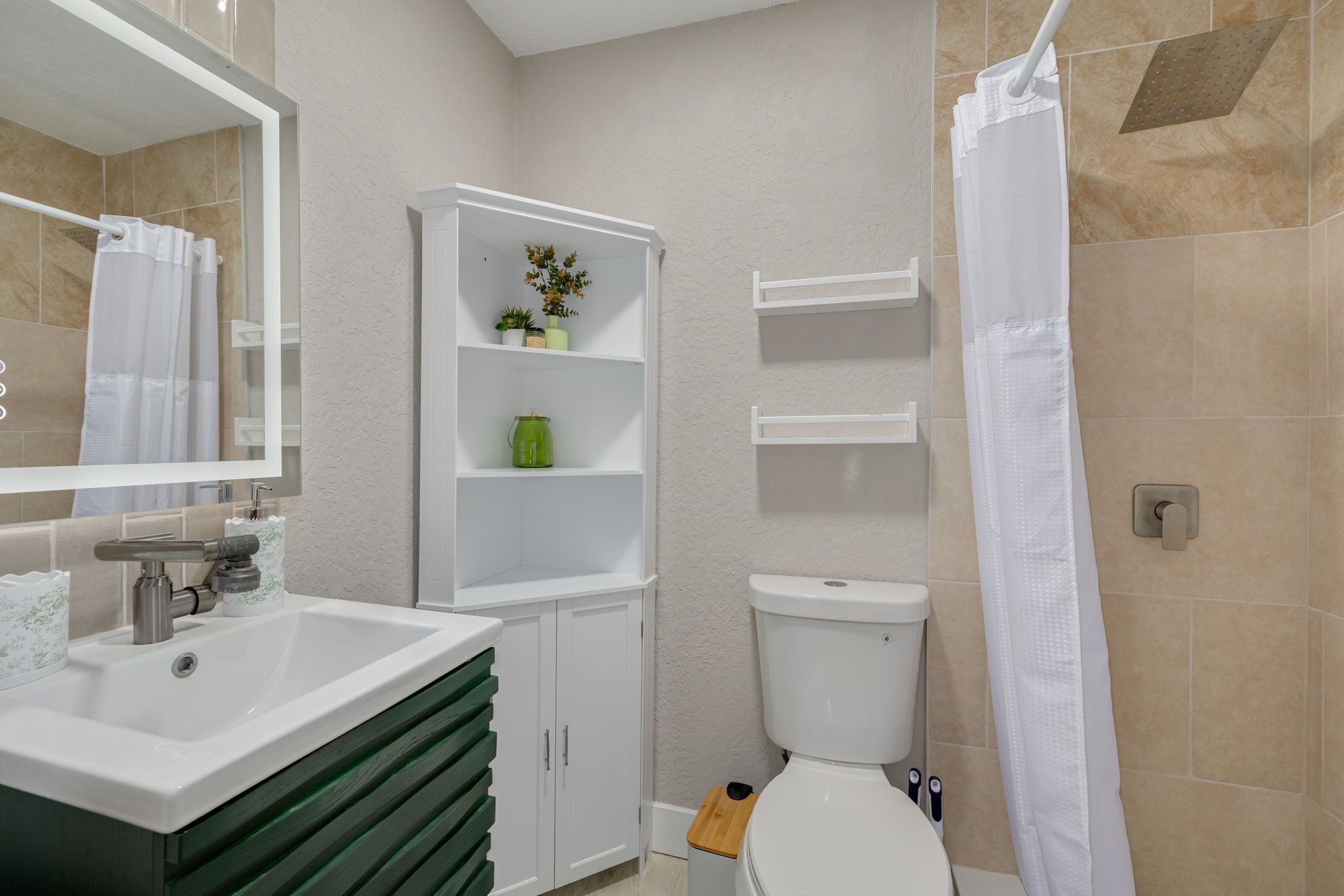 A bathroom with a white sink, a toilet, a shower curtain, and a cabinet with shelves.