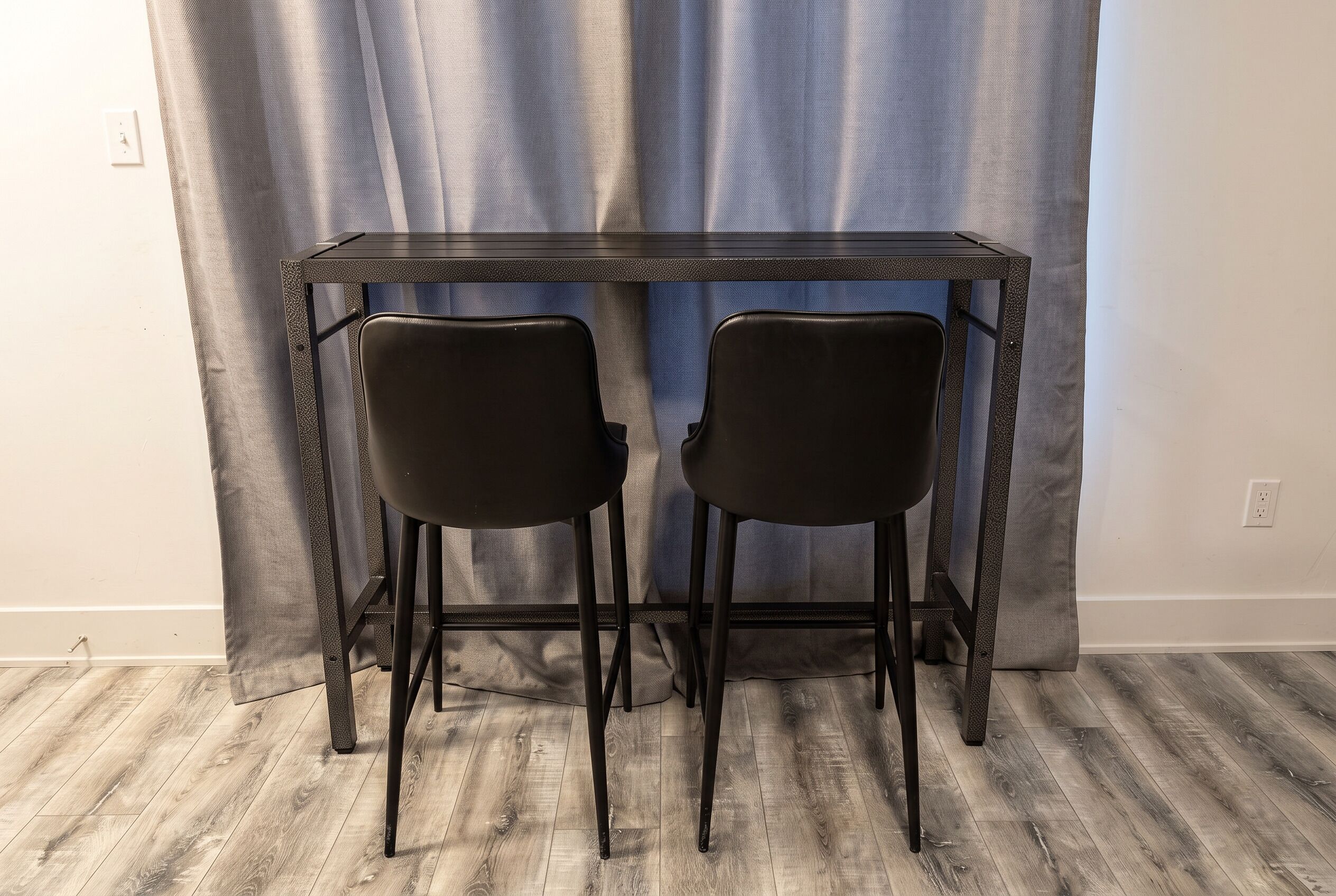 A room with a dark wooden table and two black chairs.