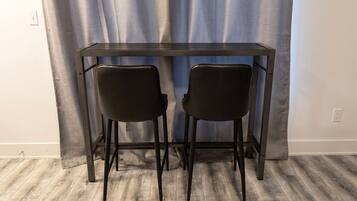 A room with a dark wooden table and two black chairs.