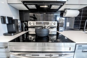 Una cocina moderna con estufa de acero inoxidable, cafetera y juego de cuchillos.