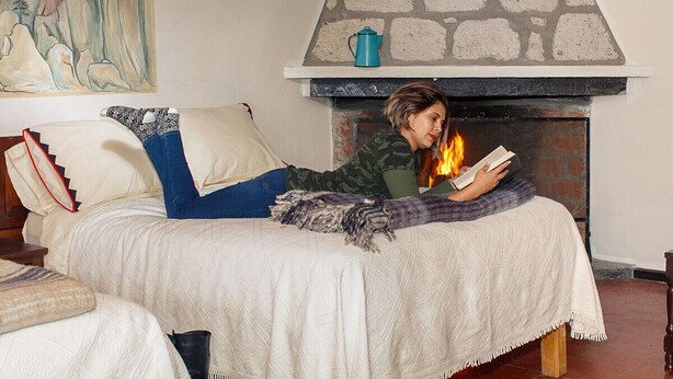 A room with a bed, a fireplace, and a painting on the wall.