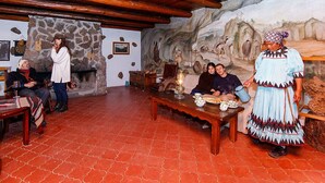 A room with a stone wall, wooden beams, a fireplace, and a mural.