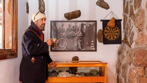 A man in a coat and hat standing in front of a display case with rocks.