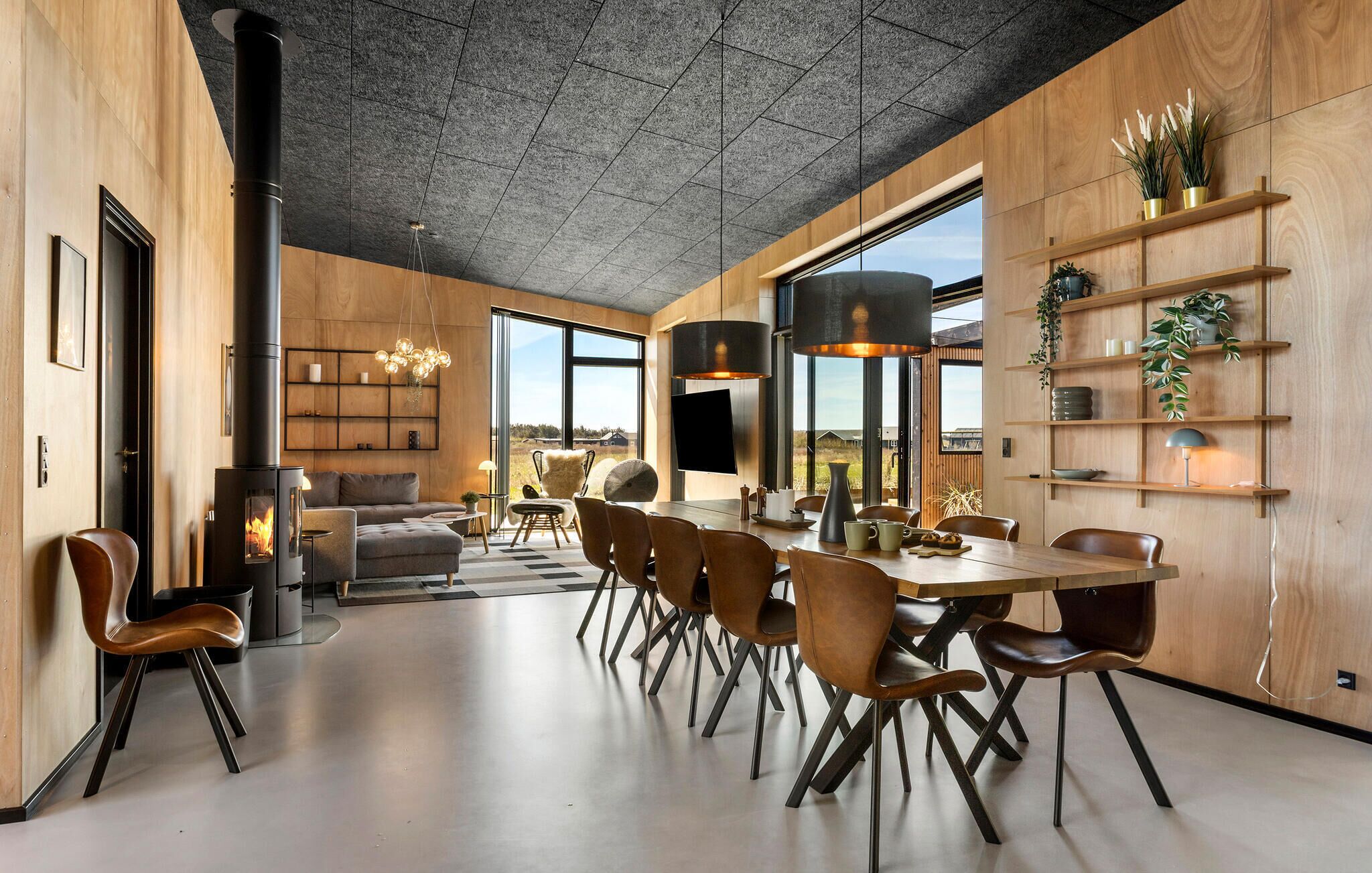 Un interior moderno con zona de comedor, sofás y chimenea.