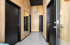 A corridor with wooden panel walls, black doors, and a glass door with a handle. - Beautiful home in Løkken with sauna (Løkken)