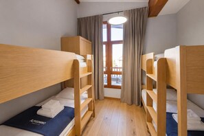 Ein Zimmer mit zwei Etagenbetten, einem Vorhangfenster und einer Deckenleuchte.