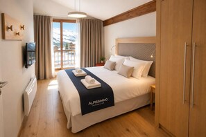 Ein Hotelzimmer mit Bett, Fernseher, Blick auf Berge und Holzboden.