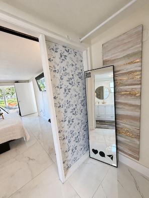 Quarto de hotel com cama, espelho grande e vista para o exterior.