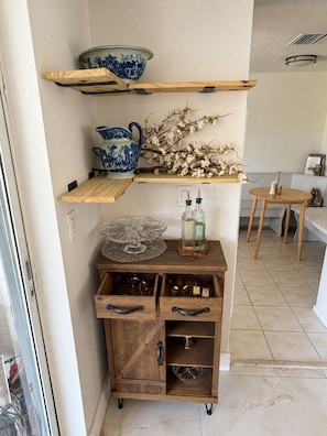 A kitchen with wooden shelves, a cabinet with drawers, and a dining area with a table and chairs. - Memories!! (Holiday)
